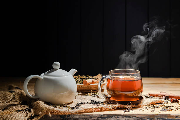 istock Hot tea in a cup, herbal tea glass with white kettle arranged on a rustic wooden table. 2207255218