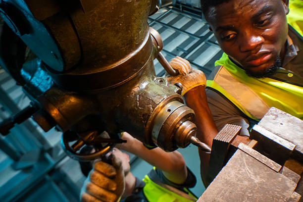 istock Focused industrial worker operating a heavy-duty drill in a workshop. The image captures precision, skill, and attention to detail, as well as the importance of safety equipment like gloves and vests. 2207255469
