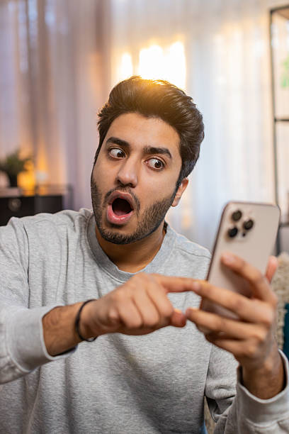 istock Happy man using smartphone scrolls through news on smartphone reacting with surprise and excitement 2207255485