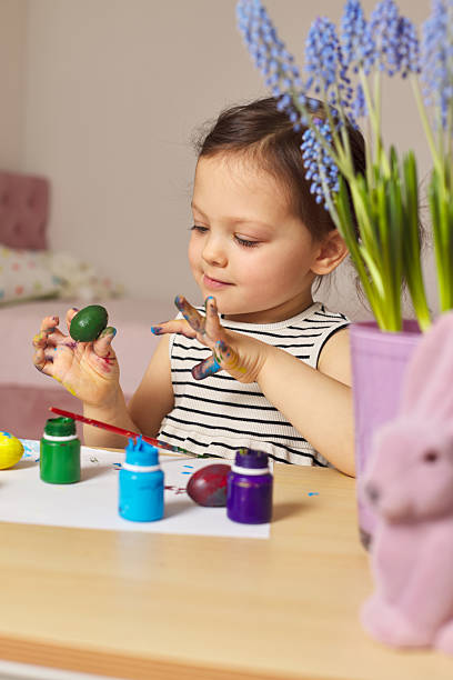 istock Little child girl paint Easter eggs at home 2207255760