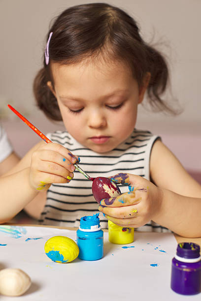 istock Little child girl paint Easter eggs at home 2207255773