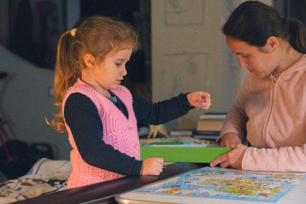 istock Leisure Games. Mom Helps Child Do A Puzzle At Night 2207255839