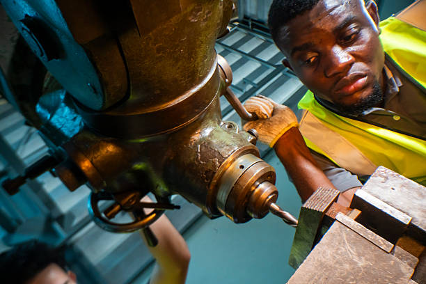 istock Focused industrial worker operating a heavy-duty drill in a workshop. The image captures precision, skill, and attention to detail, as well as the importance of safety equipment like gloves and vests. 2207255898