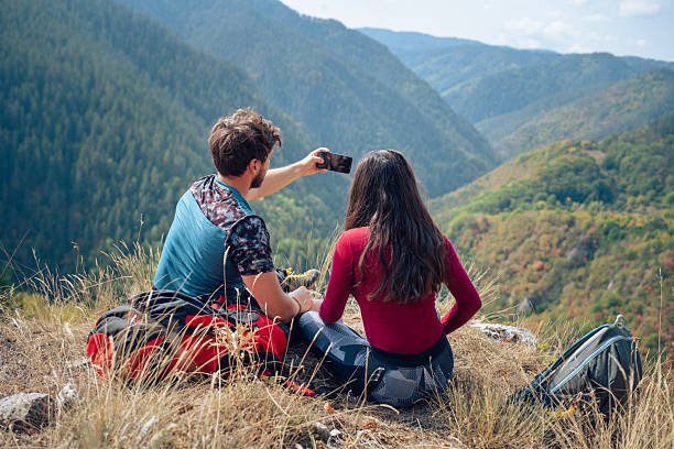 Young couple taking selfies with smartphone on a hike in nature.