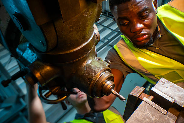 istock Focused industrial worker operating a heavy-duty drill in a workshop. The image captures precision, skill, and attention to detail, as well as the importance of safety equipment like gloves and vests. 2207256063