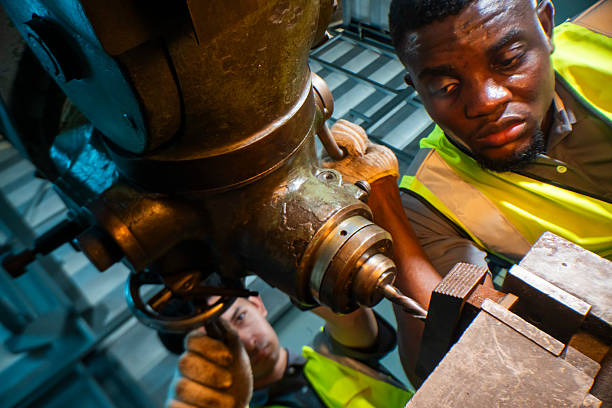 istock Focused industrial worker operating a heavy-duty drill in a workshop. The image captures precision, skill, and attention to detail, as well as the importance of safety equipment like gloves and vests. 2207256218