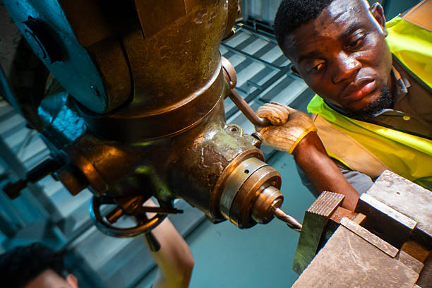 istock Focused industrial worker operating a heavy-duty drill in a workshop. The image captures precision, skill, and attention to detail, as well as the importance of safety equipment like gloves and vests. 2207256861