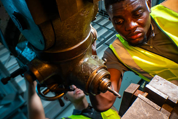 istock Focused industrial worker operating a heavy-duty drill in a workshop. The image captures precision, skill, and attention to detail, as well as the importance of safety equipment like gloves and vests. 2207257101