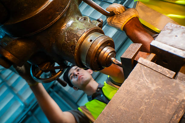istock Focused industrial worker operating a heavy-duty drill in a workshop. The image captures precision, skill, and attention to detail, as well as the importance of safety equipment like gloves and vests. 2207257217