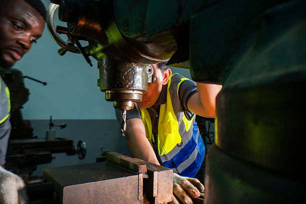 istock Two industrial workers operating a heavy-duty drilling machine in a factory. They focus on precision, wearing safety vests. The scene highlights teamwork, machinery handling, and engineering expertise 2207257311