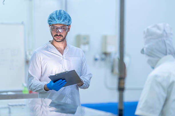 istock A food processing supervisor in protective gear inspecting packaging materials in a factory, holding a clipboard, emphasizing quality control, hygiene, and safety in food production operations 2207259171