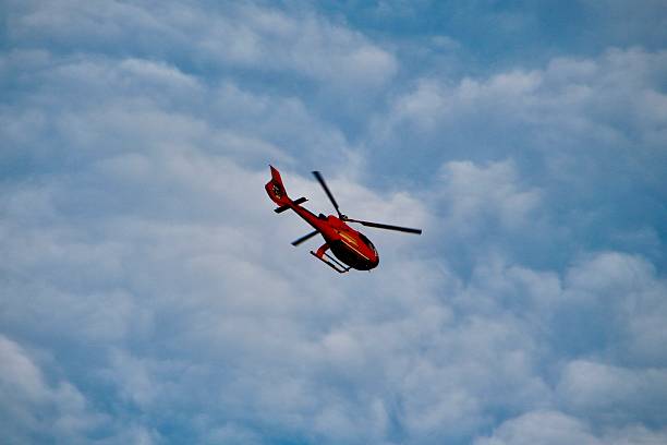 istock Red helicopter in the a sky with patchy clouds. 2207263319