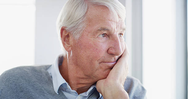 istock Retirement, senior man and thinking in home with past memory, reflection and remember old life. Window, view and elderly person with nostalgia, peaceful and daydreaming for insight, relax and calm 2207265522