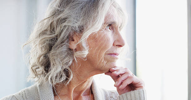 istock Thinking, retirement and elderly woman in home with reflection, idea and hope by window for view. Dementia, vision and senior person with alzheimer, nostalgia and remember past memory with peace 2207265537