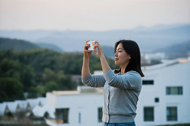 istock asian female take picture with smart phone during sunset 2207271298