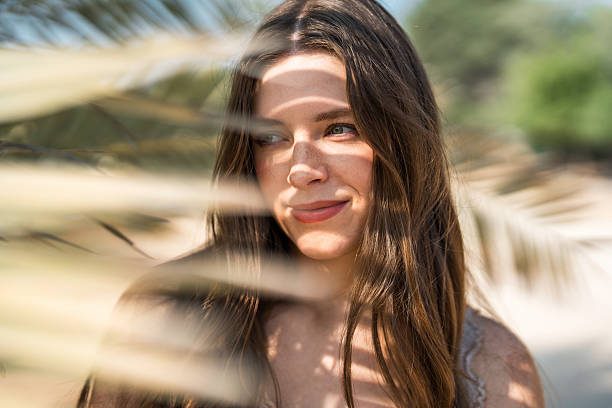 istock Young Caucasian Female Smiling Under Soft Sunlight with Palm Tree Shadows 2207284393