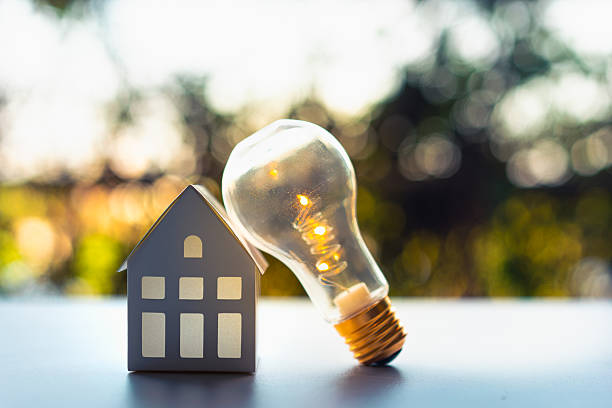 istock Light bulb with wood house on the table, a symbol for construction, Creative light bulb idea, power energy or business idea concept ecology, loan, mortgage, property or home. 2207287855
