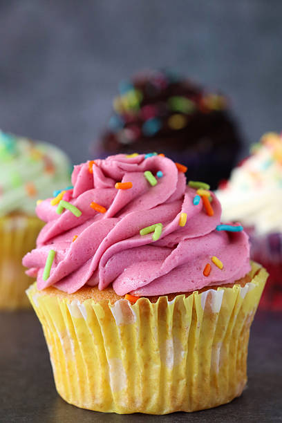 istock Image of pink raspberry cupcakes with butter icing, cream, and rainbow sprinkles / freshly baked muffins, cakes from bakery 2207287931
