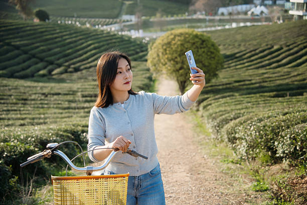 istock Asian woman is using smart phone while pushing a bicycle along the path in the tea garden 2207288617