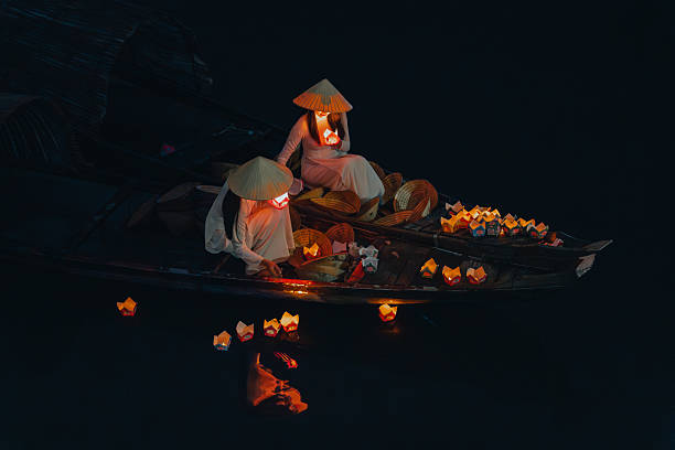 istock Traditional multicolored paper lanterns with candles floating down the river at night and beautiful woman with Vietnam culture traditional 2207289303