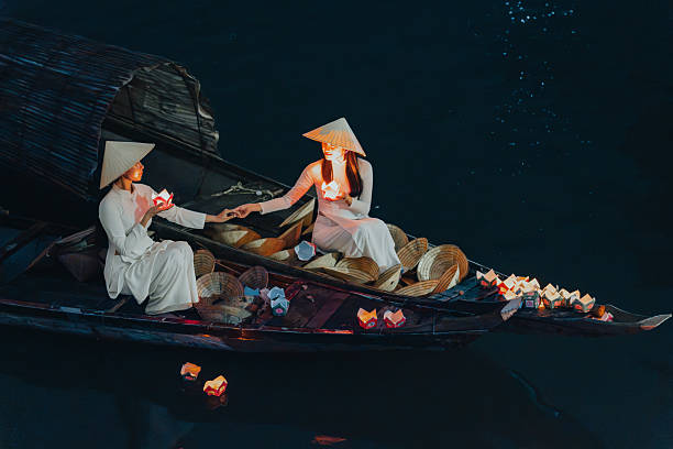 istock Traditional multicolored paper lanterns with candles floating down the river at night and beautiful woman with Vietnam culture traditional 2207289330