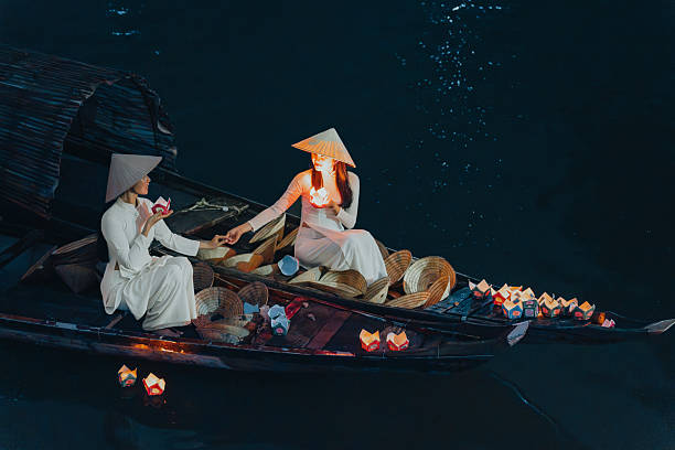istock Traditional multicolored paper lanterns with candles floating down the river at night and beautiful woman with Vietnam culture traditional 2207289335