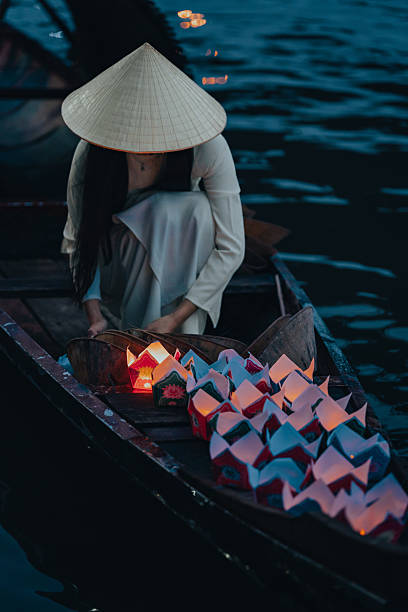 Traditional multicolored paper lanterns with candles floating down the river at night and beautiful woman with Vietnam culture traditional