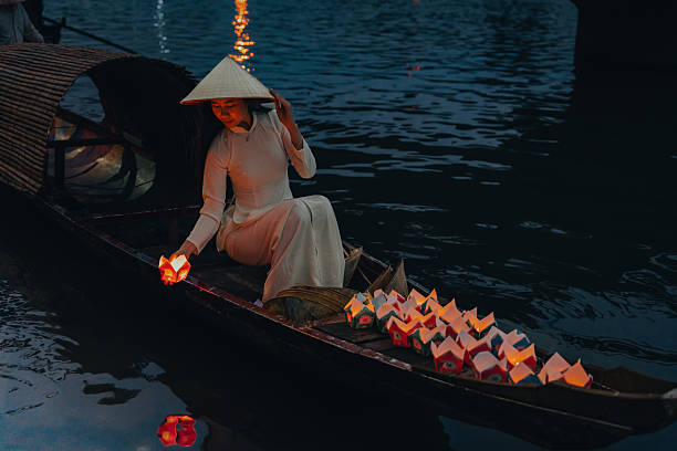 istock Traditional multicolored paper lanterns with candles floating down the river at night and beautiful woman with Vietnam culture traditional 2207289953