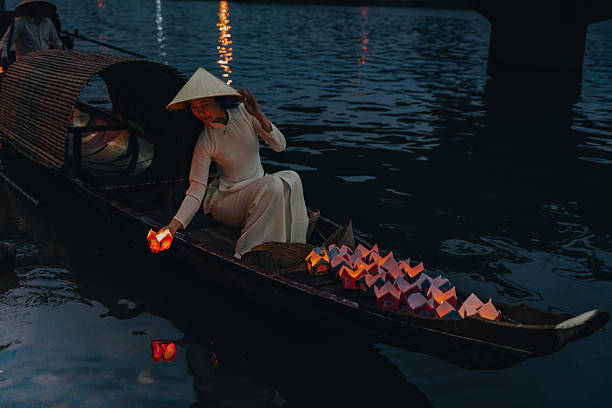 istock Traditional multicolored paper lanterns with candles floating down the river at night and beautiful woman with Vietnam culture traditional 2207289954