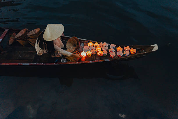 istock Traditional multicolored paper lanterns with candles floating down the river at night and beautiful woman with Vietnam culture traditional 2207289957