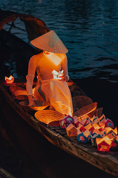 istock Traditional multicolored paper lanterns with candles floating down the river at night and beautiful woman with Vietnam culture traditional 2207289965