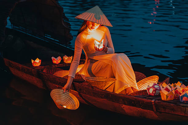 istock Traditional multicolored paper lanterns with candles floating down the river at night and beautiful woman with Vietnam culture traditional 2207289977