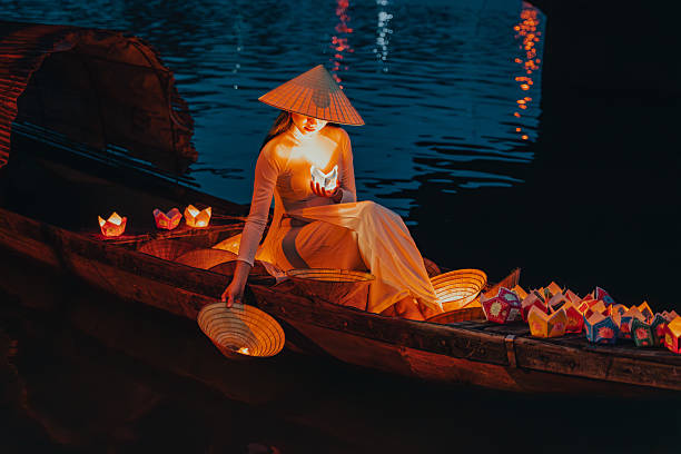 istock Traditional multicolored paper lanterns with candles floating down the river at night and beautiful woman with Vietnam culture traditional 2207289980