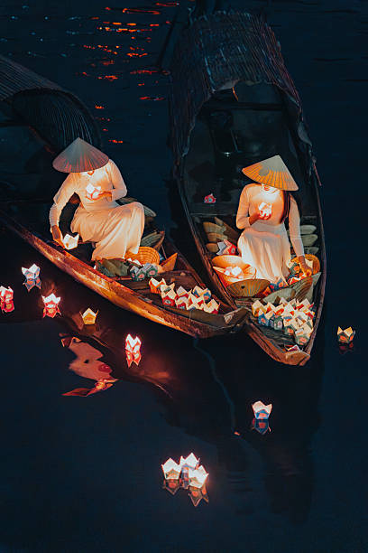istock Traditional multicolored paper lanterns with candles floating down the river at night and beautiful woman with Vietnam culture traditional 2207290024