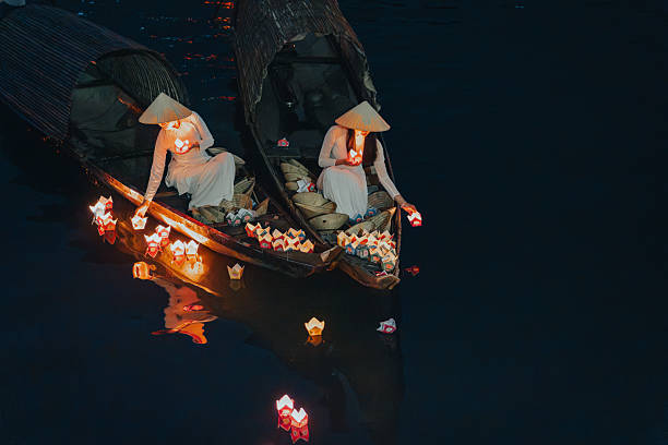 istock Traditional multicolored paper lanterns with candles floating down the river at night and beautiful woman with Vietnam culture traditional 2207290030