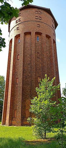 istock Tall brick water tower surrounded by green trees and grass 2207292087