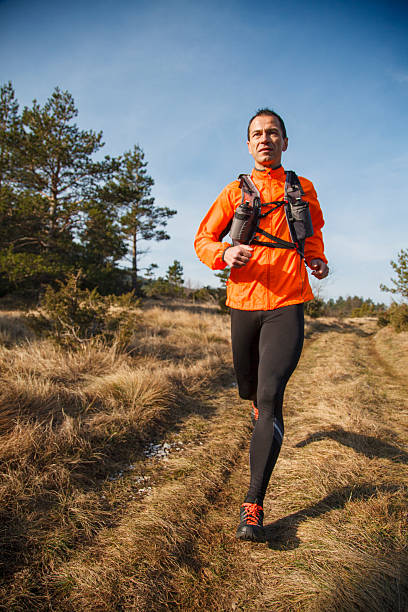 istock Man running at sunset autumn day on the mountain dirt road 2207299734
