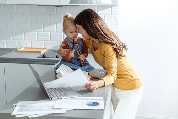 istock Mother multitasking work with toddler at home kitchen counter 2207301224