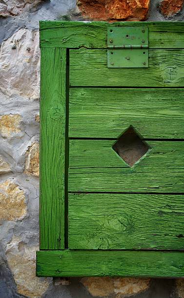 istock Closed green window shutters against stone wall 2207304006