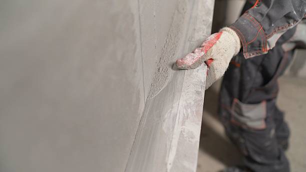 istock Plasterer using screeder smoothing putty plaster mortar on wall. Smoothing out putty on the wall. 2207306364