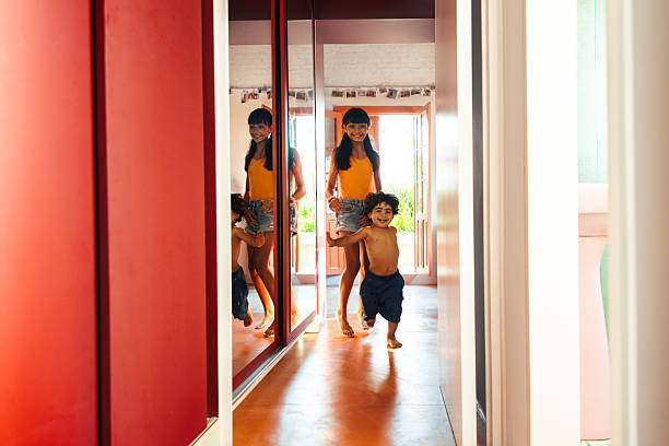 Two young siblings share a joyful moment together in a well-lit and colorful home, showcasing a sense of familial love, happiness, and togetherness.