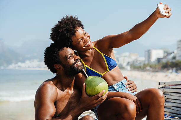 istock Joyful couple on honeymoon taking a beach selfie with coconut 2207307381