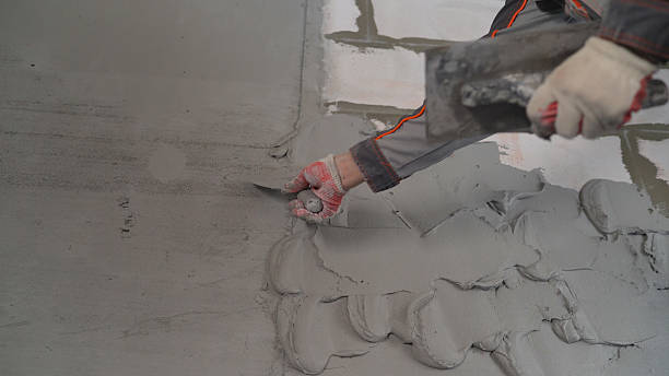 istock The worker is covering the walls with mortar. Plasterer at work on construction site, leveling walls and checking quality. Industrial worker on construction site. The process of repairing a wall using metal guides and mortar. 2207307918