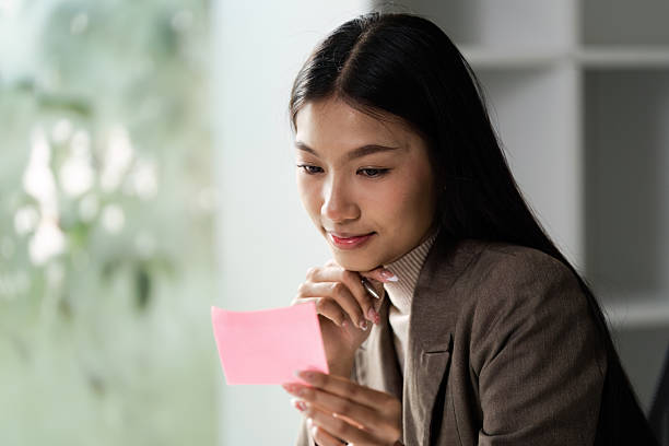 istock Thoughtful woman analyzing sticky note in a contemporary workspace, highlighting focus and creativity. 2207308160