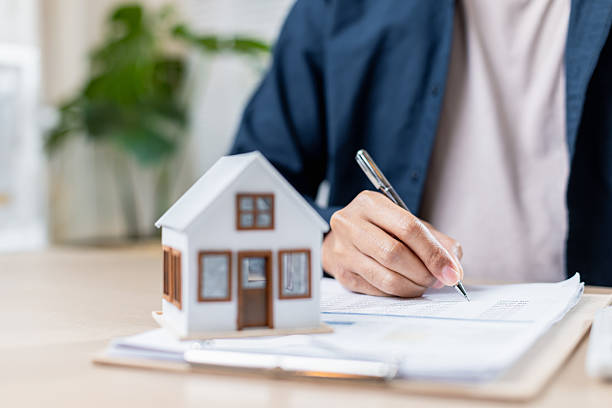istock person signing documents with house model on desk 2207310177