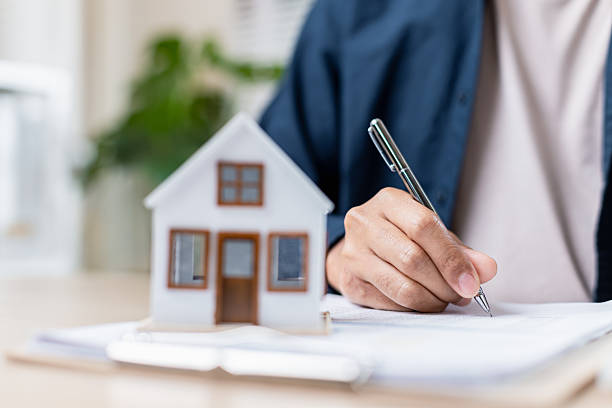 istock person signing document with house model nearby 2207310190