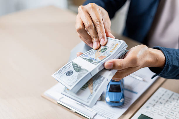 istock person counting stack of hundred dollar bills at desk 2207310201