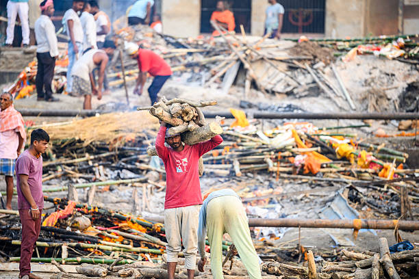 Varanasi, India - November 3, 2024: indian men carrying firewood at central cremation place at Ganges riverside in Varanasi