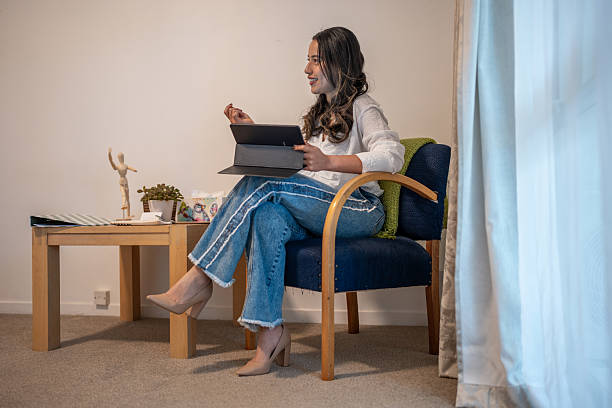 istock Woman Sitting Indoors Holding Tablet and Talking 2207312593