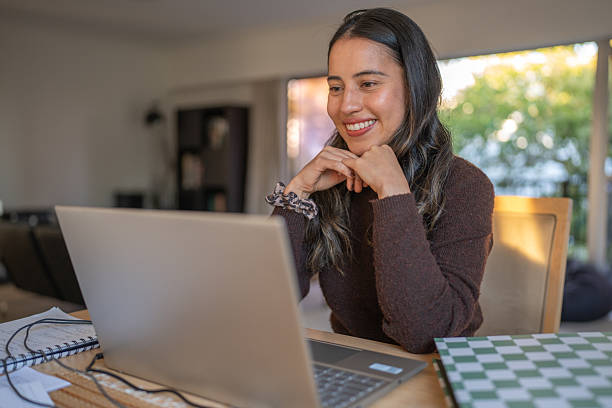 istock Smiling Woman Watching Laptop Screen at Home 2207312810